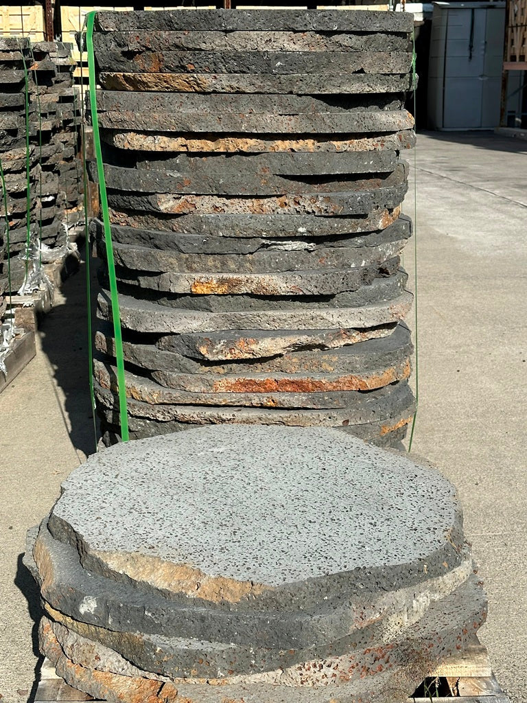 Stack of stone slabs on a pallet with a large stone in the foreground.